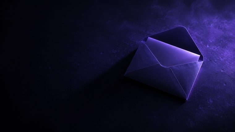An opened envelope on a dark desk, lit in purple