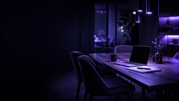 A home dining table set up as a boardroom, lit in purple